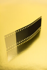 Fototapeta na wymiar Fragment of 35 mm film on golden surface.