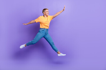 Full length photo of pretty carefree person jumping look empty space isolated on violet color background