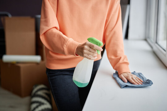 Close-up of young woman using detergent to do housework in her new apartment after relocation