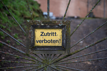 Close-up yellow german Zutritt verboten, access forbidden sign on a old metal fence at Ronneburg...