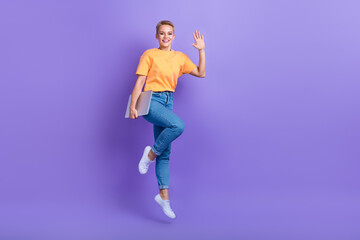 Fototapeta na wymiar Full length photo of excited carefree person jumping hold netbook arm palm waving hi isolated on violet color background