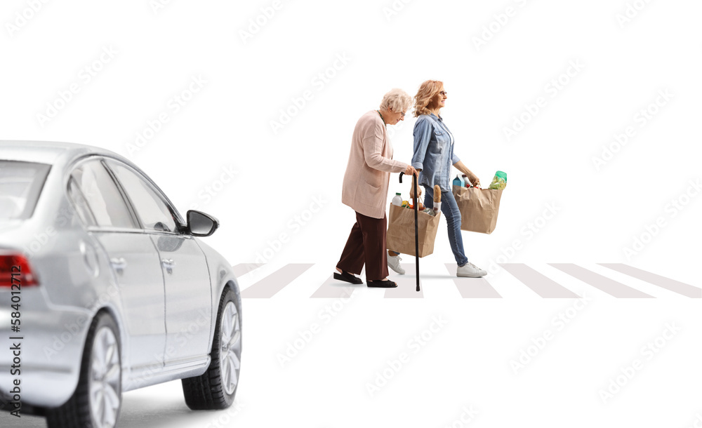 Wall mural car driving towards a pedestrian crossing, a woman with an elderly lady crossing street and carrying