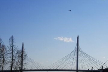 A military helicopter in the blue sky over the city.