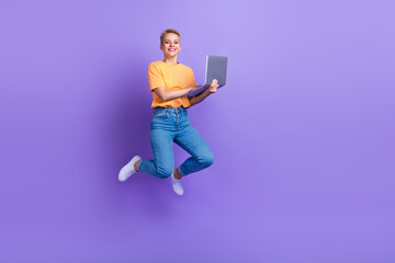 Full length portrait of carefree excited person jumping use netbook empty space isolated on purple color background
