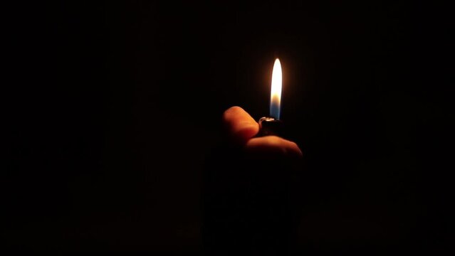 Man's hand with a gas lighter. A man kindles a fire. slow motion footage. slow motion light fire gas lighter in the dark. a lighter flame on a black background. ignited by sparks. The lighter.