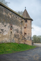 Fototapeta na wymiar Walls with Tower of Ronneburg Castle with street in front during cloudy day, Germany, vertical shot