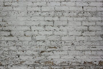 Old brick wall with peeling white paint.