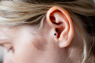 Outer ear black tragus piercing on blonde female