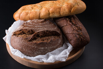 Fresh round black bread with a crispy crust. Close-up on a black background