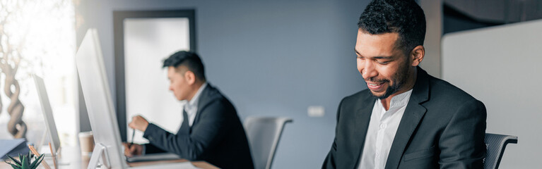 African businessman taking notes during working day in office on colleague background