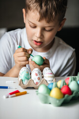 Child paints eggs with different colors.
