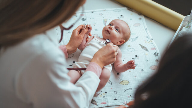Doctor examining small kid with stethoscope in clinic. Doctor listening small childs lungs with stethoscope. Close up of pediatrician hand using a stethoscope to listen and checking heartbeat.