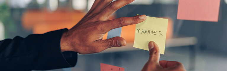 Businesswoman hand's is sticking sticky notes on business board in office