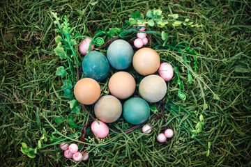 Fototapeta na wymiar Easter wreath with eggs in grass against blurred green background. Spring holidays concept