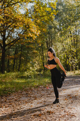 A young girl with black hair with a beautiful athletic figure goes in for sports in the morning while jogging in an autumn forest dotted with yellow leaves