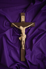 Crucifix on a dark purple fabric background with copy space