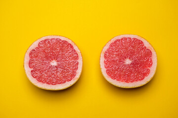 Juicy organic grapefruit cut in half on a yellow background. Cool minimal flat lay, copy space. Healty breakfast or diet concept.