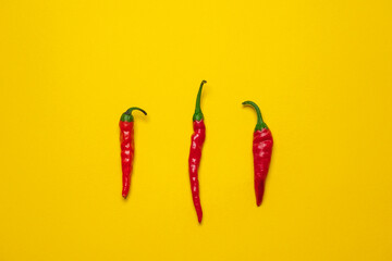 Calabrian red hot chilli peppers on a yellow background. Cool minimal flat lay, copy space
