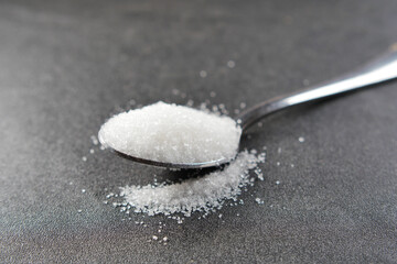 white sugar on a silver spoon on table 