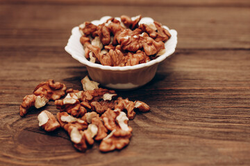 Obraz premium Dried walnut grains in a bowl on a wooden table.