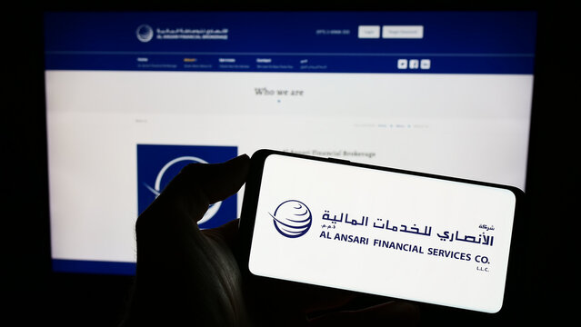 Stuttgart, Germany - 03-18-2023: Person holding mobile phone with logo of Arabian company Al Ansari Financial Services on screen in front of web page. Focus on phone display.