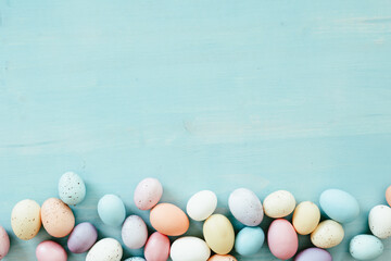 Border of easter eggs on a blue wood background with copy space