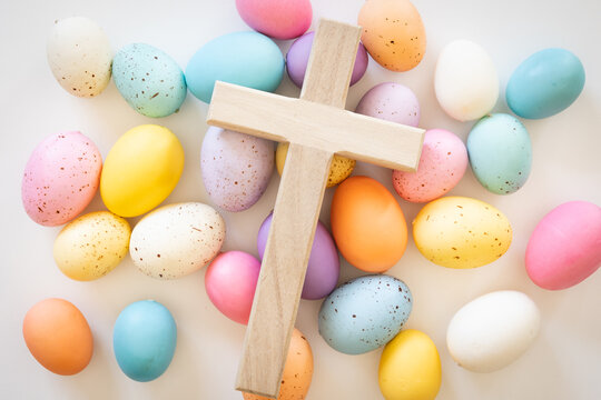 Wood cross on a background of pastel easter eggs