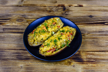 Plate with baked stuffed eggplants on a wooden table
