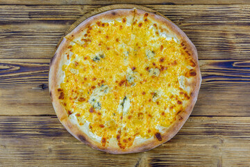 Pizza quattro formaggi (four cheeses) on a wooden background. Top view