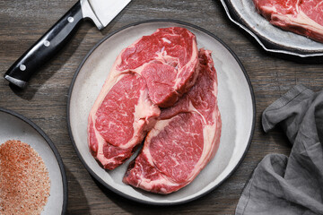 Slices of raw beef fillet steaks on plate on a wooden table. Top view. 