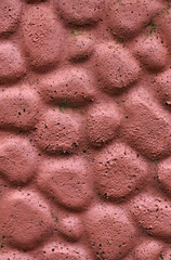The texture of the concrete wall is made to look like stone and painted red-brown