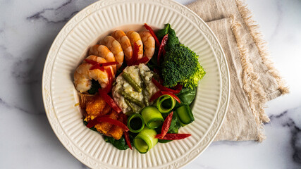Shrimp bowl, with poached shrimp, asparagus risotto, orange supremes, shaved cucumber, and broccoli. All on a bed of baby spinach and garnished will grape tomato slivers.