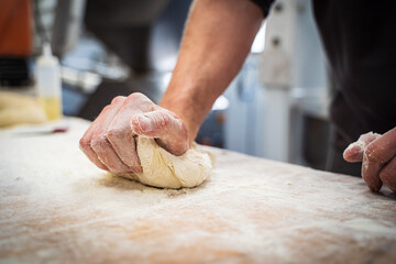 Hands kneading dough on a wooden table with flour