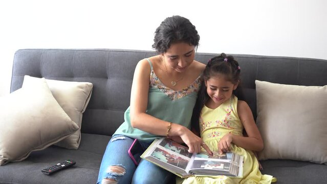 Mom and daughter looking at a photo album laugh and spend quality time together