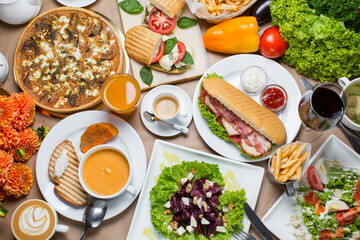 breakfast on the table, french fries on table with vegetables, sweet pepper, coffee, soup with meatballs and sandwich