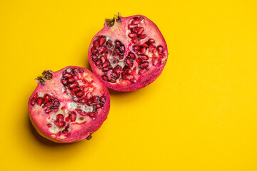 A juicy Pomegranate cut in half on a yellow background. Cool minimal flat lay, copy space