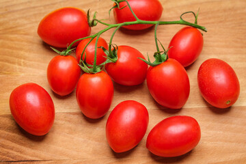 San marzano DOP cherry tomato branch with ripe, little tomatoes on a wooden cutting board.