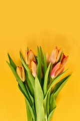 Flower bouquet with orange tulips on yellow background with copy space