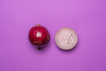 Organic whole and sliced red onion on a purple background. Cool minimal flat lay, copy space