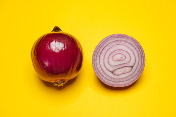 Organic whole and sliced red onion on a yellow background. Cool flat lay, copy space