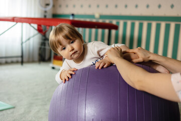  baby is doing physiotherapy exercises on the ball, Physiotherapist with happy baby doing exercises...