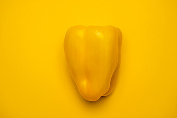 A juicy organic yellow pepper on a yellow background. Cool minimal flat lay, copy space