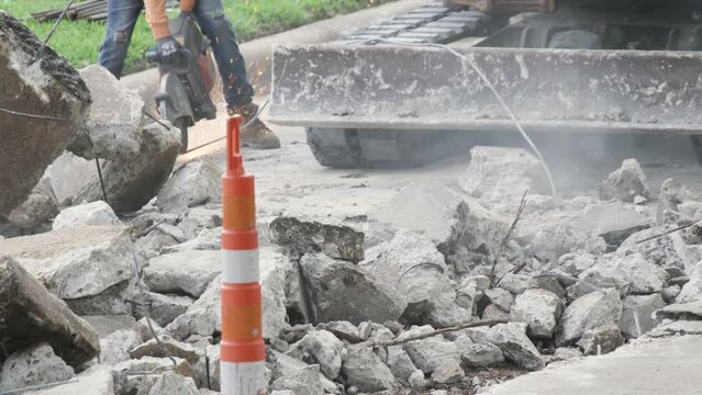 excavator moving concrete debris from street