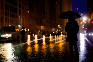 Silhouettes of woman on the rainy street in big city.