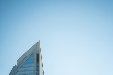 Fototapeta na wymiar Reaching for the Sky: Tall Skyscraper Soars into the Wide Blue Sky