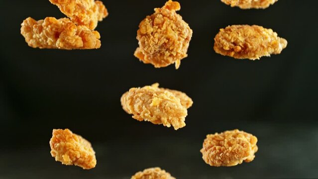 Super slow motion of flying fried chicken pieces on black background. Filmed on high speed cinema camera, 1000fps, placed on high speed cine bot. Camera in motion, following objects.