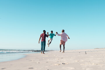 Happy african american grandfather with adult son and grandson playing at beach