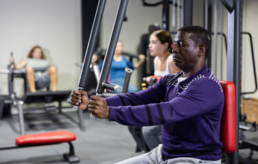 African-american man training on chest fly machine in gym