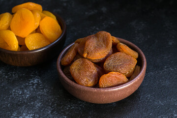 Obraz na płótnie Canvas Dried apricot various designed on wooden bowl on black surface.Conceptual image