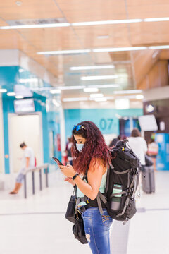 Public transport station destination. latin mid woman vacation with smartphone. with face mask